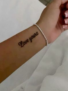 a woman's arm with the word love you on it and a small bracelet