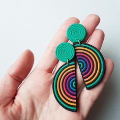 a hand holding a pair of colorful earrings