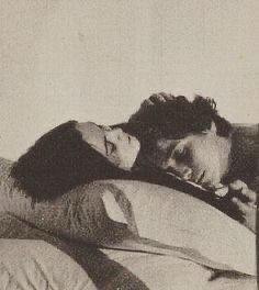 an old black and white photo of two people sleeping on a bed