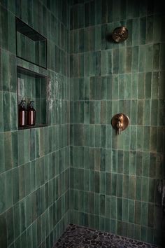 a green tiled bathroom with two copper faucets and soap dispensers