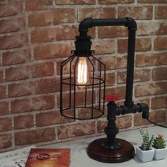 a lamp that is on top of a table next to a book and potted plant