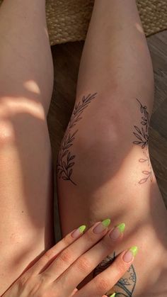 a woman's legs with green nail polish and tattoos