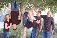 three people are hanging upside down from a tree and one person is holding onto another man's leg