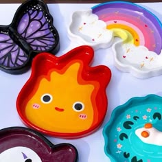 colorful plates with different designs on them sitting next to a butterfly, rainbow and sun