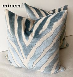 two blue and white pillows sitting next to each other on top of a table with the words mineral printed on it