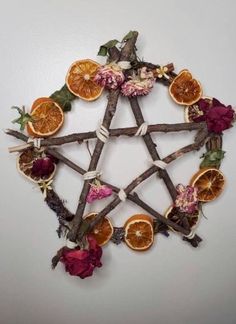 an arrangement of dried fruit arranged in the shape of a pentagram with leaves and flowers