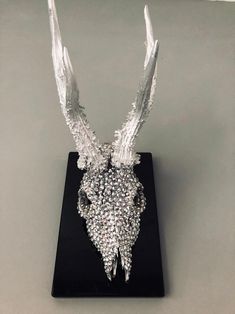 an animal head made out of crystal stones on a black stand with silver wings and beads