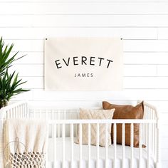 a white crib with pillows and a sign on the wall