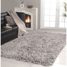 a living room with a couch, fireplace and rugs on the floor in front of it