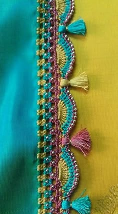 an embroidered piece with tassels and beads on the bottom is laying on a yellow cloth