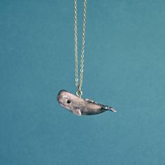 a necklace with a small bird on it's side hanging from a gold chain