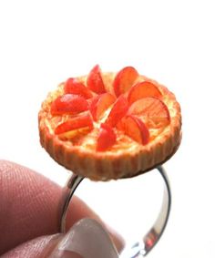 a tiny orange pie sitting on top of a silver ring