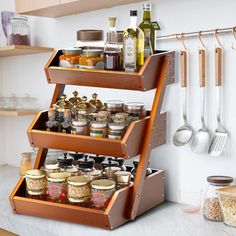 a wooden spice rack filled with spices on top of a counter next to utensils