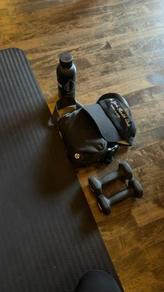 a gym mat, water bottle and dumbbells are on the floor next to a bag