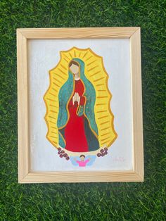 an image of the virgin mary in a wooden frame on green grass with sun rays