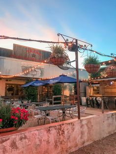 an outdoor dining area with tables, chairs and umbrellas at dusk or dawn in the evening