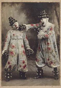 two creepy clowns are standing next to each other