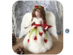 an angel figurine with white fur and red berries on its wings holding a pine cone