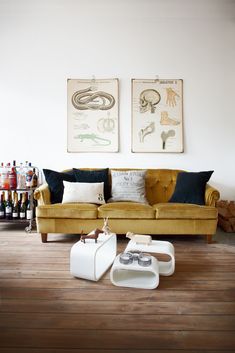 a living room filled with furniture next to two pictures on the wall and wine bottles