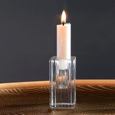 a lit candle sitting in a clear glass vase