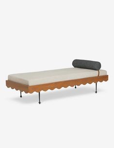 a bed with scalloped legs and a pillow on it's back end