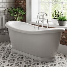 a white bath tub sitting in a bathroom next to a window with potted plants