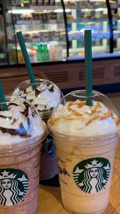 two starbucks drinks sitting on top of a wooden table