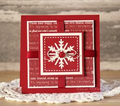 a red and white christmas card with snowflakes on it sitting on a doily