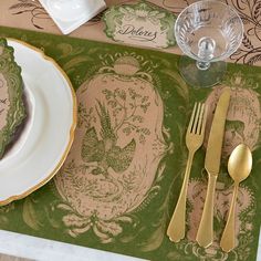 the place setting is ready to be served with goldware and green napkins,