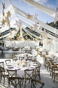 tables and chairs are set up for an event with stars hanging from the ceiling above them