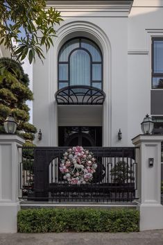 a wreath is placed on the front gate of a white house with black iron railings