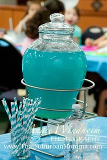 a blue table topped with a large glass jar filled with liquid and paper straws