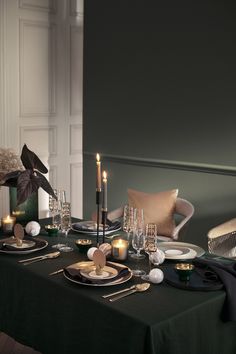 a table set with candles, plates and silverware