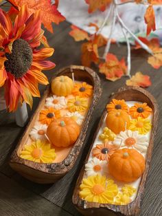 two wooden trays filled with fake pumpkins and flowers