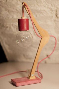 a wooden table lamp with a red light bulb on the base and a pink cord attached to it