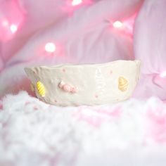 a small white bowl sitting on top of a bed covered in pink and yellow decorations