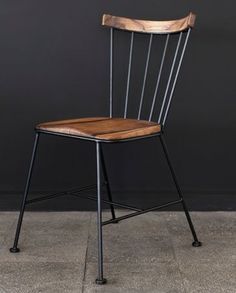 a wooden chair sitting on top of a cement floor next to a blackboard wall