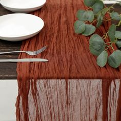 the table is set with silverware, plates and red cloth draped over it to give an elegant touch