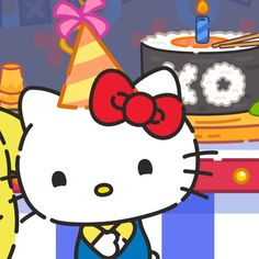 a hello kitty birthday cake with candles and a cat wearing a party hat standing in front of it