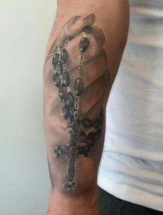 a man with a rosary and cross tattoo on his arm