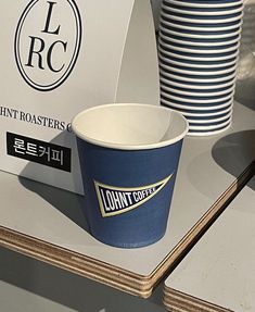 a blue coffee cup sitting on top of a table next to stacks of paper plates