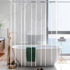 a white bath tub sitting under a window next to a sink and a towel rack