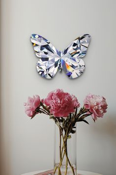 a vase filled with pink flowers next to a butterfly cutout