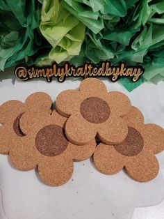 several cork coasters sitting on top of a white table next to green paper flowers