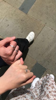 two people are holding hands and touching each other's fingers while sitting on the ground