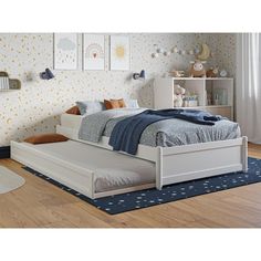 a white bed sitting on top of a wooden floor next to a book shelf filled with books