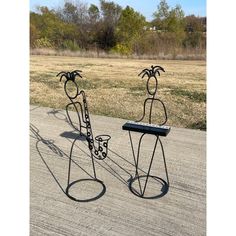 two metal sculptures sitting on top of a cement road next to a grass covered field