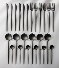 an assortment of spoons and forks on a white surface