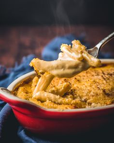 a spoon full of macaroni and cheese being lifted from a casserole dish