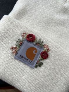 there is a white beanie with red flowers on it and the name carnifini